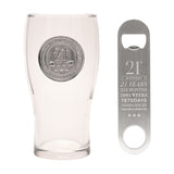 Clear glass pint beer glass with raised silver 21st badge and three stars, paired with a matching stainless steel bottle opener engraved with 21st Birthday milestones, on a white background.