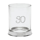 Round glass whisky tumbler with a raised 3D silver "30" on the side and "THIRTY" engraved on its silver base, shown on a plain white background.