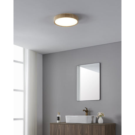 Musurita LED bathroom ceiling light with round white diffuser and natural wood-effect rim, shown flush-mounted above a grey bathroom with mirror and washbasin.