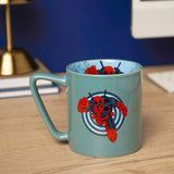 Green porcelain Deadpool mug with a C-handle, featuring a red and black target graphic on the outside and a matching inside decal, shown on a desk.