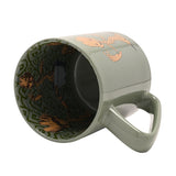 Green porcelain Avengers Groot mug tipped on its side, showing the handle and an inside decal of Groot figures amid swirling vine patterns, set against a white background.