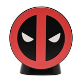 Round resin money box featuring the Deadpool emblem in red and black with white glaring eyes, set on a curved black stand against a plain white background.