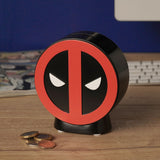 Round Deadpool Emblem resin money box in red and black with moulded relief design, top coin slot, and curved stand, shown on a desk beside loose coins.
