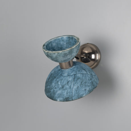 Nakaii Ceramic Wall Light in Blue Earth, a mottled blue double-dome shade with upward bowl and downward dome joined by a silver metal collar and arm, on a plain grey background.