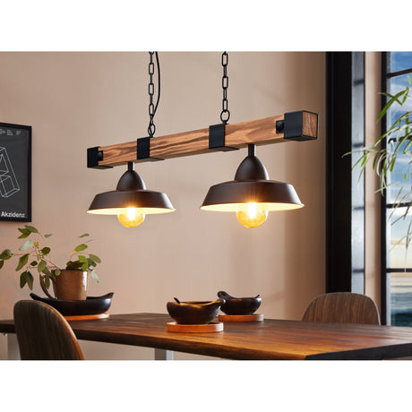 Narmessa 2 Light Pendant in black and brown, featuring a wooden beam with black steel brackets and two dome shades on chains, shown hanging above a dining table.