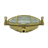 Small Cabin round bulkhead light in raw brass with a ribbed glass dome, brass cage grille, and thumb-turn lugs, shown front-on against a white background.