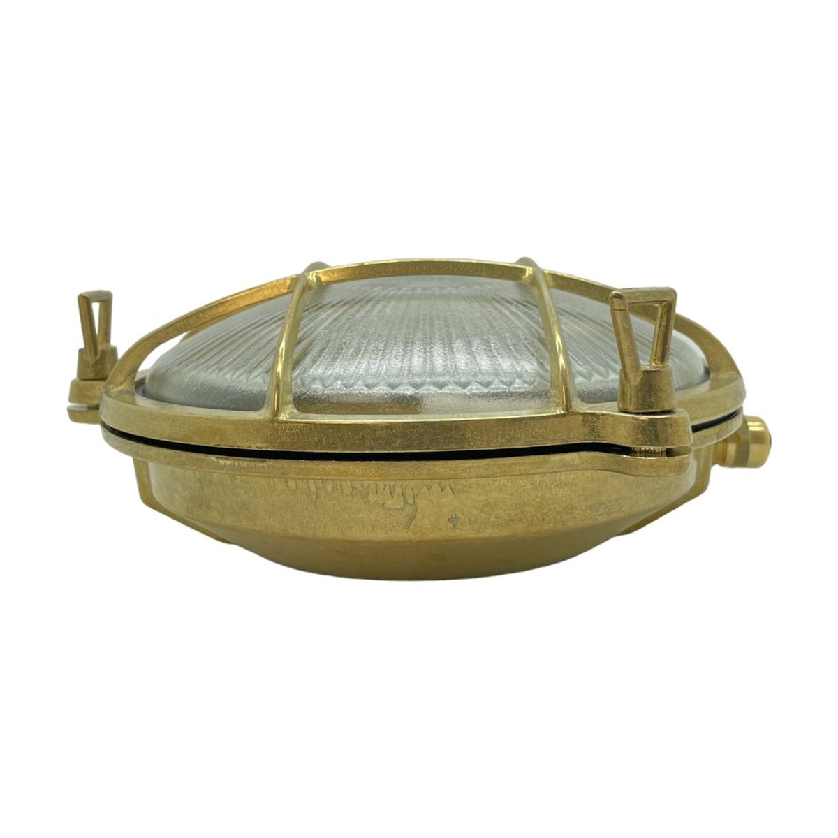 Small Cabin round bulkhead light in raw brass, with ribbed glass dome, brass cage grid, and thumb turn fixings, shown on a white background.