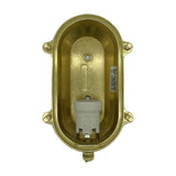 Interior view of the Palaemon Eyelid Bulkhead Light in raw brass, showing the oval housing, E27 ceramic lampholder, mounting lugs, and cable gland on a white background.