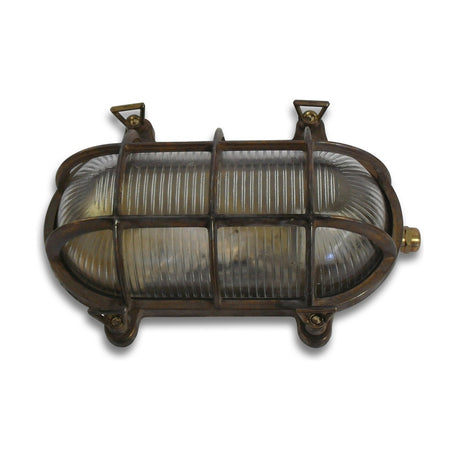 Horatio Oval Bulkhead Light in antique brass finish, IP64 outdoor wall light with ribbed glass diffuser, brass cage, corner lugs and gland, shown on a white background.