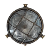 Grand Cabin round bulkhead light in antique brass with a lattice grid over ribbed glass lens and mounting lugs, shown on a plain white background.
