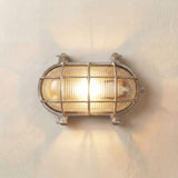 Horatio Oval Bulkhead Light in satin nickel, illuminated on a wall, with ribbed glass, caged bars, and corner lugs, IP64 rated.