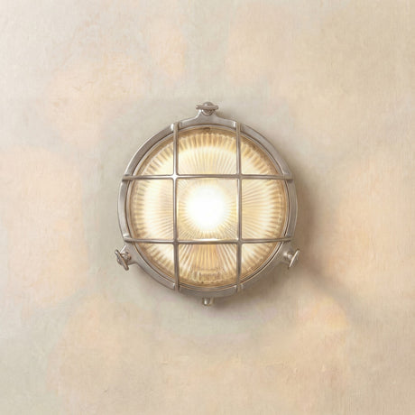 Grand Cabin round bulkhead light in satin nickel, with grid cage over ribbed glass lens lit from within, mounted on a plain pale wall, IP64 rated.