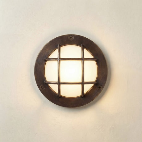 Marina Guard Circular Bulkhead Light in antique brass, round wall fixture with a cross-bar grid guard over a frosted glass diffuser, mounted on a plain light wall.