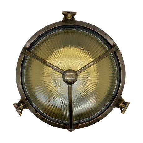 Trident Round Bulkhead Light in antique brass, featuring a three-arm cage guard over ribbed glass and three mounting brackets, shown against a plain white background.