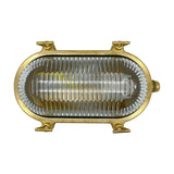 Small Siren oval bulkhead light with solid raw brass body and ribbed clear glass cover, no front grille, shown against a plain white background.