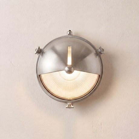 Trident Shield round bulkhead light in satin nickel, brass body with ribbed glass, half-moon shield and three fixing lugs, mounted on a plain light wall.