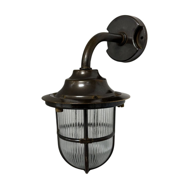 Quinn Guard outdoor wall lantern in antique brass, with a goose-neck arm, wide hood, and ribbed glass shade in a cage guard, shown on a white background.