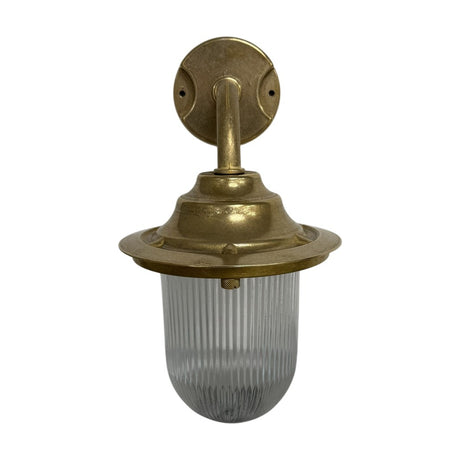 Quinn Outdoor Wall Lantern in raw brass with a gooseneck arm, round wall plate, flared hood and clear ribbed glass dome, IP64 rated, shown on a plain white background.