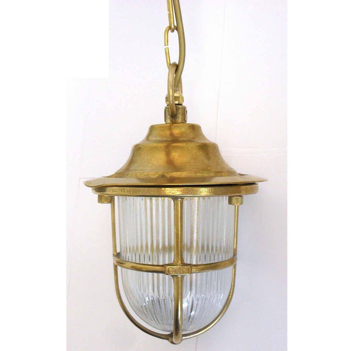 Hull Guard outdoor pendant light in raw brass, with ribbed glass shade encased in a brass cage guard and stepped hood, hung on a chain against a white background.