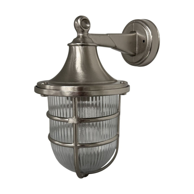 Grand Tiller outdoor wall lantern in satin nickel, solid brass with a flared hood, caged clear ribbed glass shade, and round wall-mount plate, shown on a plain white background.