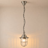 Hull Guard IP54 outdoor pendant light in satin nickel, a caged lantern with ribbed glass shade on a long chain, shown illuminated against a plain light background.