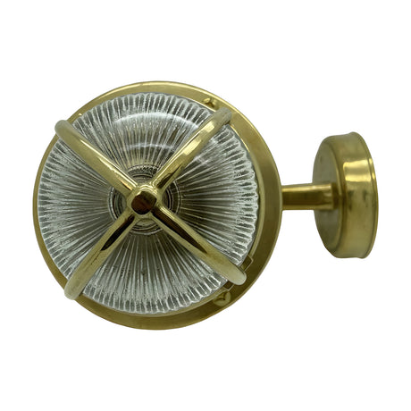 Tiller IP64 outdoor wall lantern in raw brass, with ribbed glass shade behind crossed brass guard bars on a round wall plate, shown front-on against a white background.