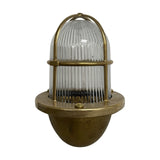 Armada Outdoor Wall Lantern in raw brass, caged uplight design with ribbed glass dome and brass bowl base, shown on a plain white background.