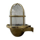 Armada Uplight Outdoor Wall Lantern in raw brass, with ribbed glass dome and brass cage guard on a curved wall bracket, shown on a plain white background.