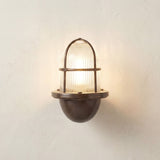 Armada Uplight Outdoor Wall Lantern in antique brass with ribbed glass dome and arched cage guard, lit against a plain light background.