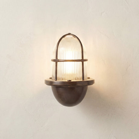 Armada Uplight Outdoor Wall Lantern in antique brass with ribbed glass dome and arched cage guard, lit against a plain light background.