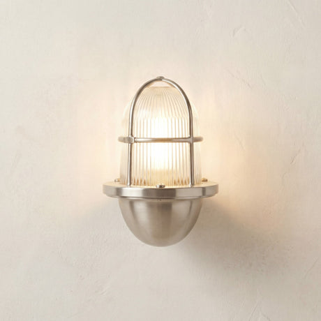 Armada Uplight Outdoor Wall Lantern in satin nickel, with caged ribbed glass dome and rounded brass base, shown illuminated against a plain light wall.