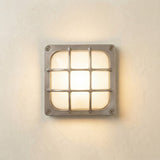Francis Outdoor Wall Light in satin nickel, a square bulkhead fixture with a crossed-bar grid cage over a frosted glass diffuser, illuminated and mounted on a light wall.