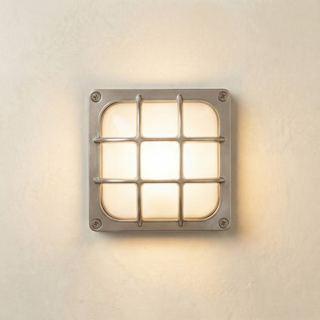 Francis Outdoor Wall Light in satin nickel, a square bulkhead fixture with a crossed-bar grid cage over a frosted glass diffuser, illuminated and mounted on a light wall.