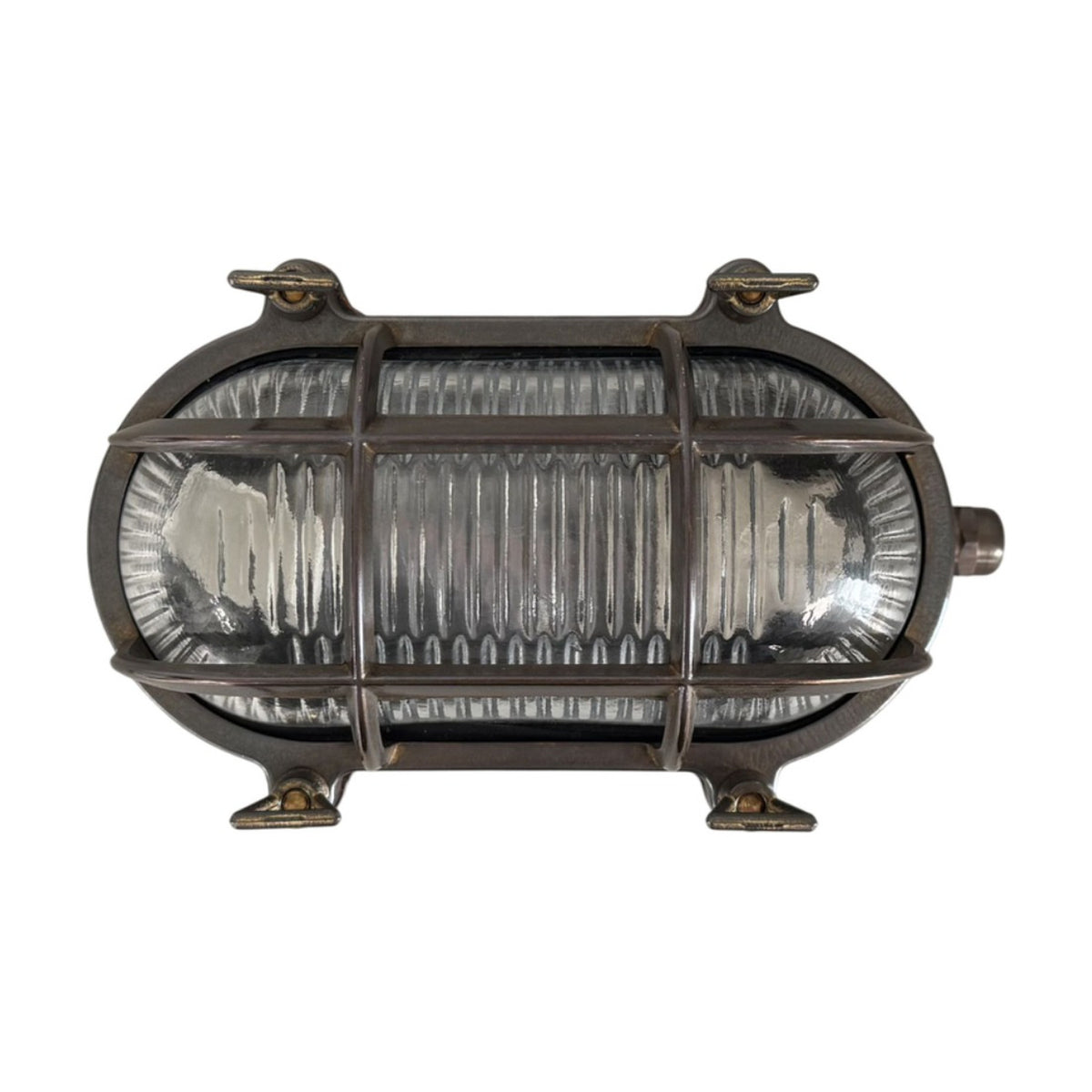 Horatio Junior oval bulkhead light in antique brass finish with ribbed glass diffuser, crossing brass cage bars, and four wall fixing lugs, shown on a white background.