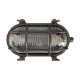 Horatio Junior oval bulkhead light in antique brass finish with ribbed glass diffuser, crossing brass cage bars, and four wall fixing lugs, shown on a white background.