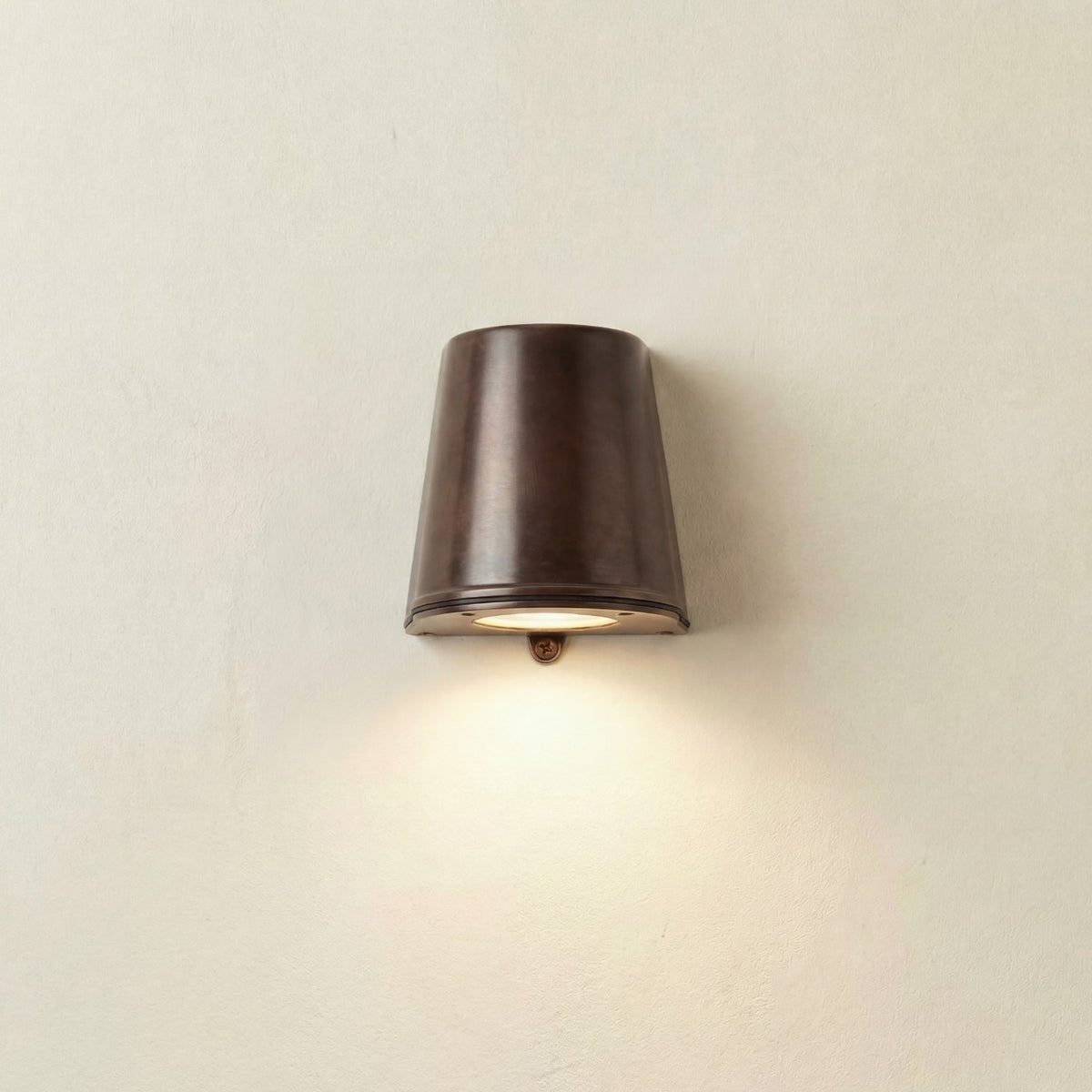 Mast Outdoor Wall Light IP65 in antique brass, a tapered bucket-shaped downlight mounted flat against a plain wall, casting light downward.