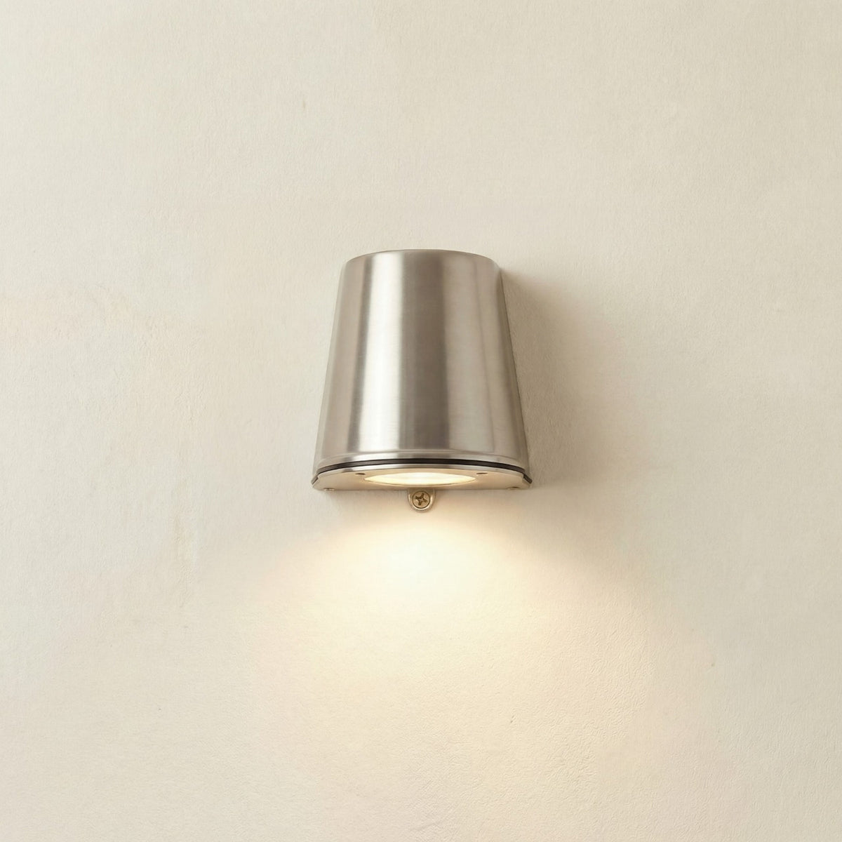 Mast Outdoor Wall Light IP65 in satin nickel, a tapered brass cylinder on a light wall, casting downward light through its base, IP65 rated.