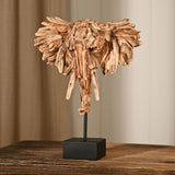 Driftwood Elephant Head Resin Figurine with Stand in brown, featuring fanned ears, downward tusks and curled trunk on a black base, shown on a wooden table.