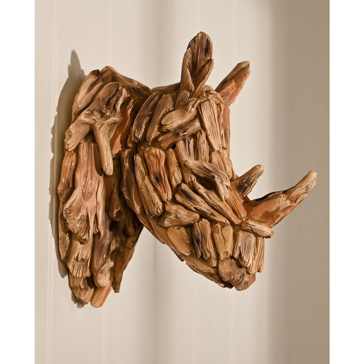 Textured Driftwood Effect Rhino Head Resin Wall Art in brown, showing layered wood-like pieces forming the muzzle, horns and upright ears, mounted on a plain wall.