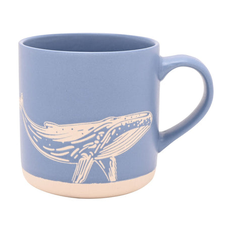 Blue stoneware mug with a cream-line whale design wrapped around the side, cream base band, and matching blue loop handle, shown on a plain white background.