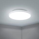 Nelbenne LED Downlight 31.5cm in white, a round flush ceiling light with flat diffuser, shown illuminated on a ceiling in a plain room corner setting.