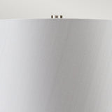 Close-up of a Neptune 1 Light Table Lamp - Blue Glaze, showcasing a light gray lampshade with a smooth texture. The design includes a small, silver knob at the top center against a light gray background and is enhanced by polished nickel accents.