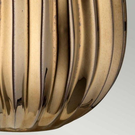 The Newham 1 Light Small Table Lamp features a bronze ceramic base and a shiny, ribbed surface with vertical grooves. Its pearl-textured satin shade elevates the lighting, accentuating the smooth, reflective texture and gold-toned color of the material for a luxurious look.