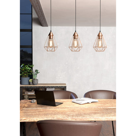 Nilbine Linear Pendant Light in Copper, three open wire-cage steel shades hung at staggered heights above a wooden dining table in a living-dining room.