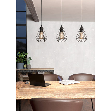 Nilbine Linear Pendant Light in matt black steel, three geometric wire-cage shades with exposed bulbs, shown above a dining table in a living space.