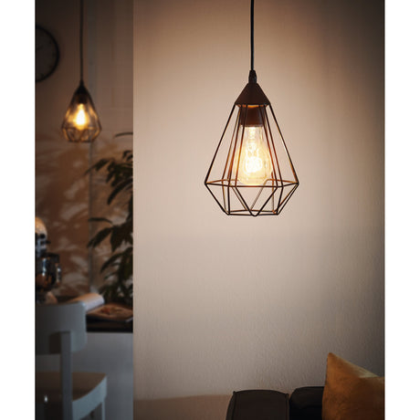 Nilbine Pendant Light 17.5cm in matt black, a diamond-shaped open cage shade with visible E27 bulb, shown hanging in a living room setting.