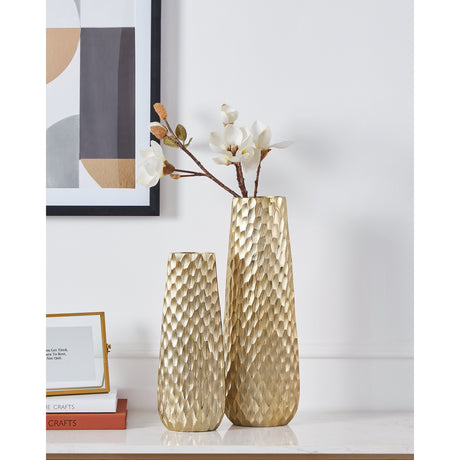Nilgaut Vase 40.5cm in brushed brass aluminium with a hammered, faceted surface, shown with white stem flowers on a console table beside a smaller matching vase.
