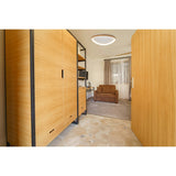 Mantra Niseko flush ceiling light with light brown wood-effect triangular frame and central diffuser, installed in a bedroom with wardrobes and sofa.