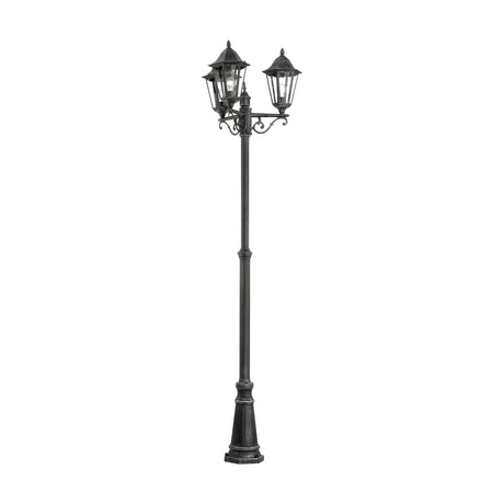 Nolmane 3 Light Lamp Post with scrolled arms and hexagonal glazed lanterns, cast aluminium in black with silver patina, pointed finials, on a plain white background.
