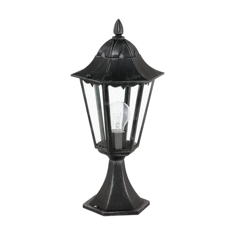 Nolmane Bollard Light in black and silver patina, a hexagonal lantern with clear glass panels, pointed finial and flared pedestal base, shown with bulb on a white background.